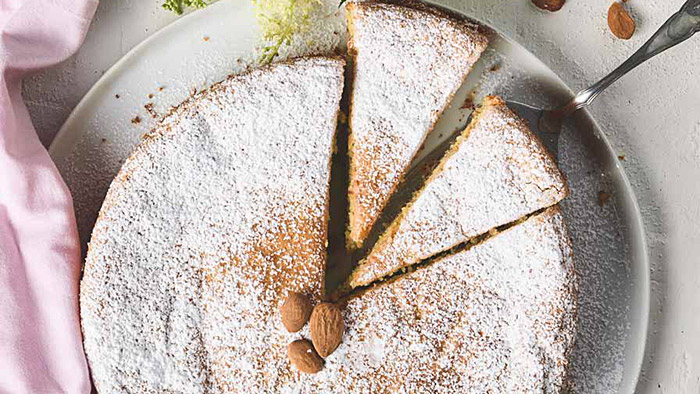 Rezept für mallorquinischen Mandelkuchen mit Mädesüß Mandelkuchen mit Kuchenschaufel. | © Joel Schindler / Louis Kaiser