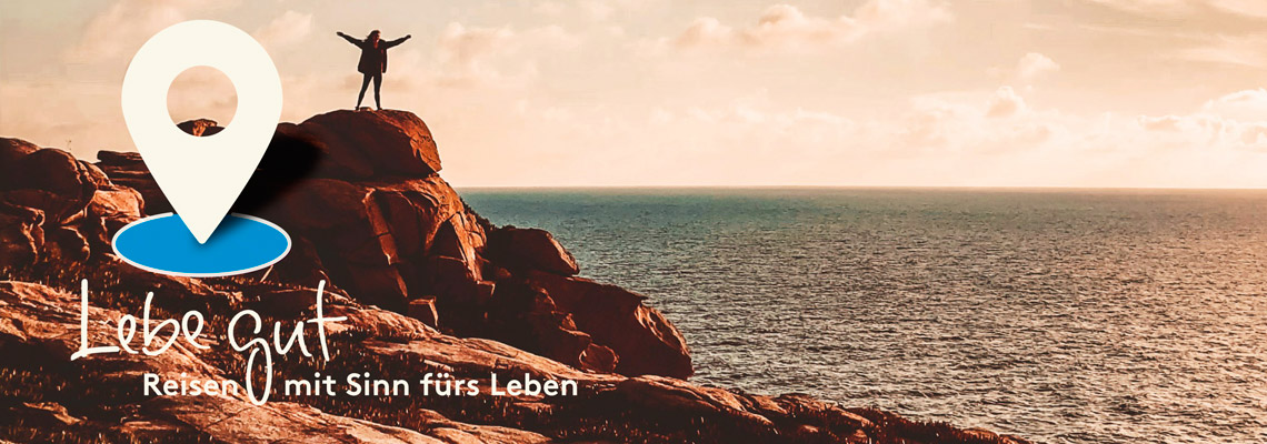 Lege gut – Reisen mit Sinn fürs Leben - ein Mann steht auf einem Felsen am Meer mit ausgebreiteten Armen